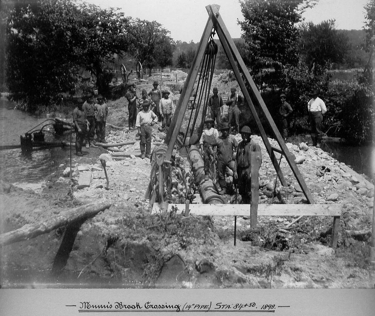 Men laying pipe with rope and pulley