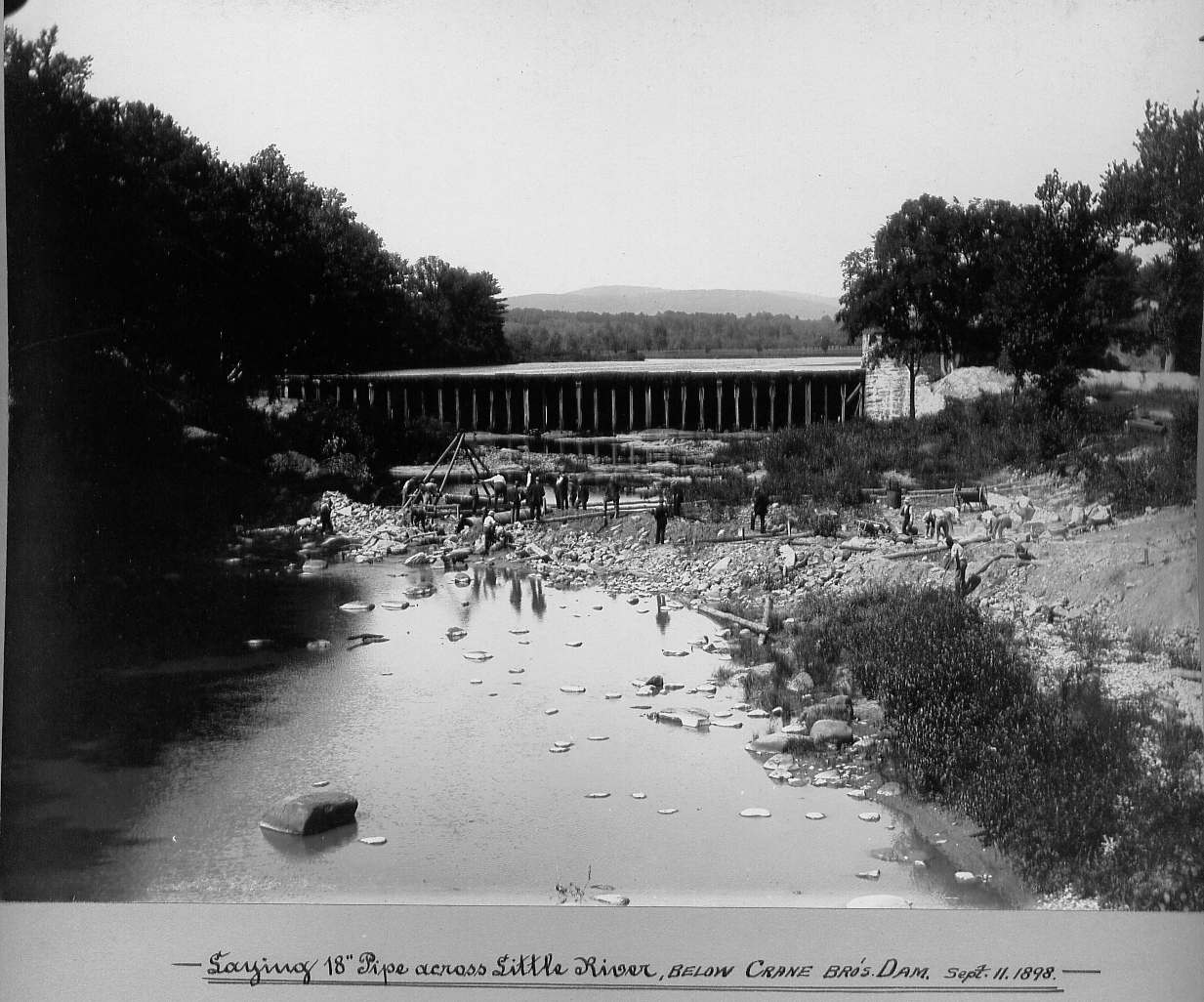 Men laying pipe below dam