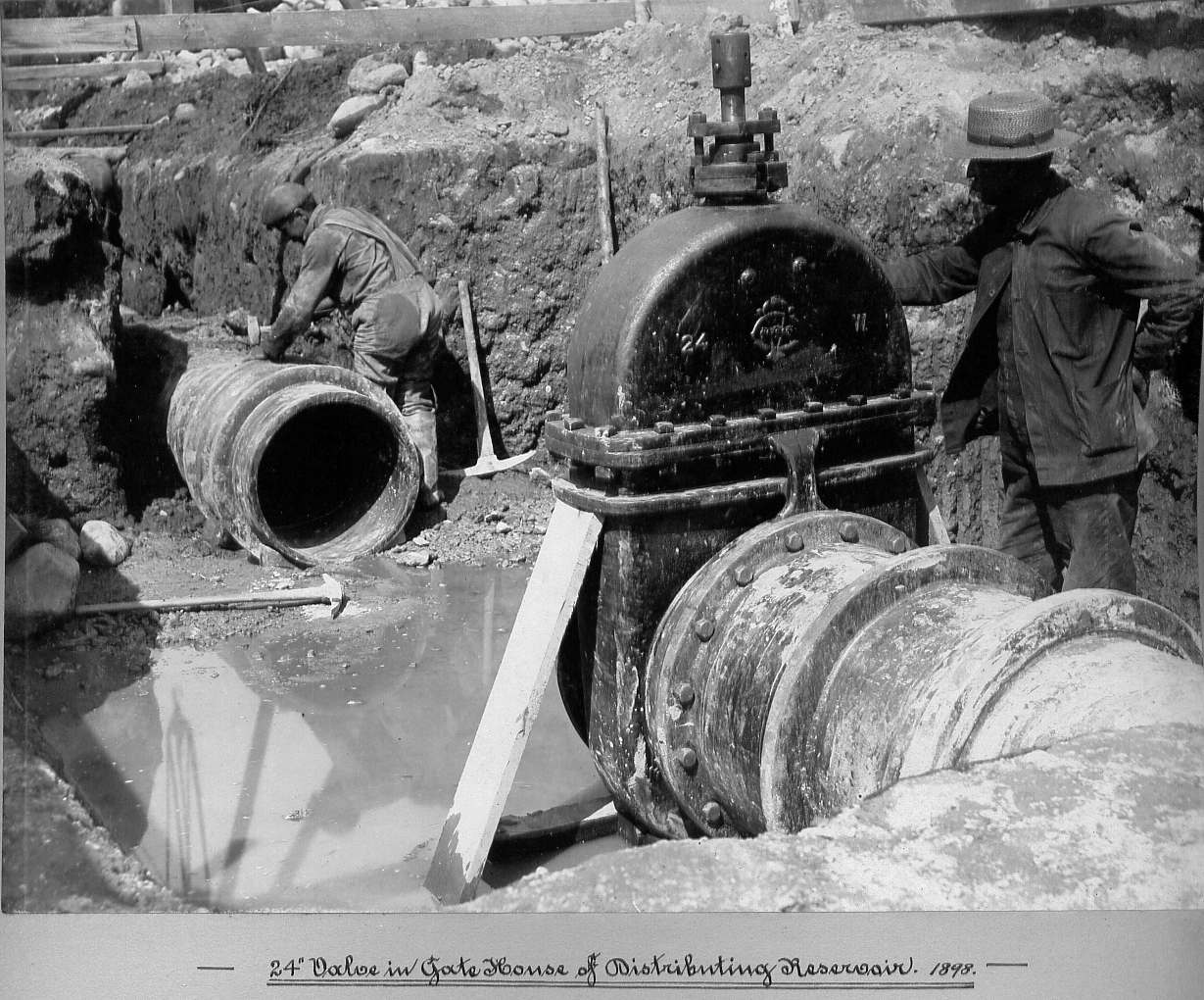 Man laying pipe and man standing next to valve