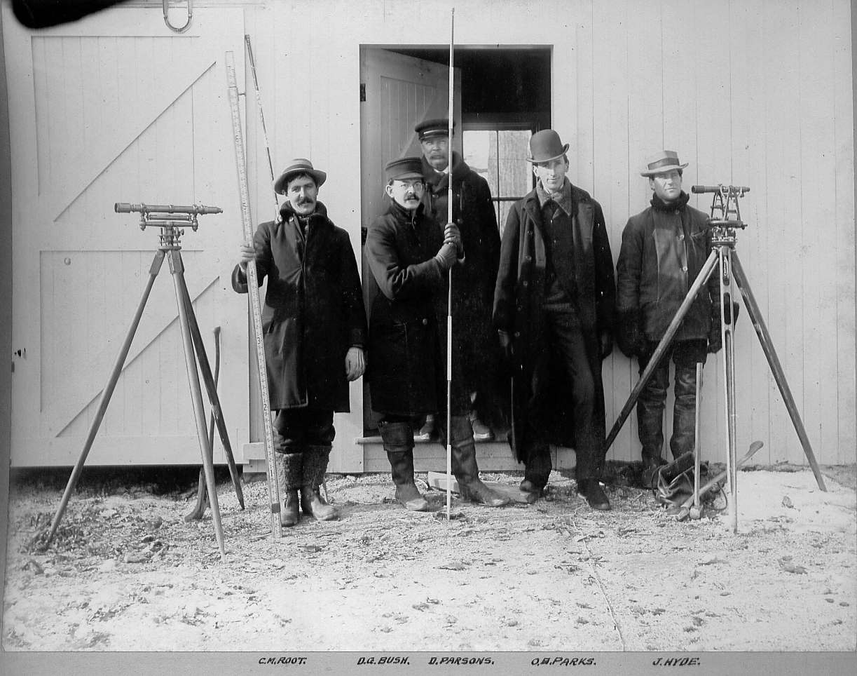 Men standing with transits and surveying poles